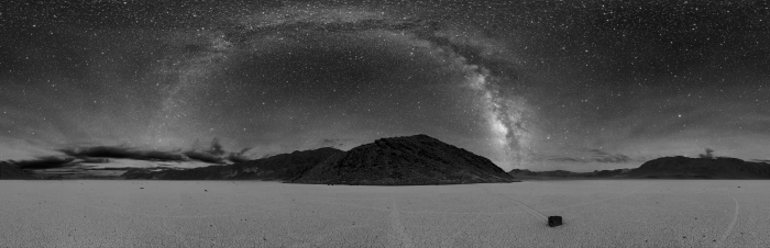 Photograph of Death Valley showing a panorama of the entire sky, which includes an arc of glowing light, which is the band of star light we call "The Milky Way".