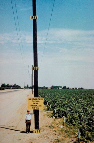 A man standing by a pole that marks the amount of land subsidence in the San Joaquin Valley as a result of overpumping for irrigation