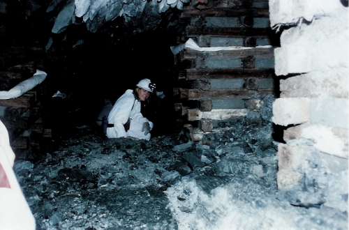 Eliza wearing white coveralls and a headlamp inside a gold mine
