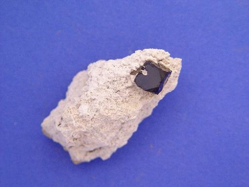 photograph of handsample of rhyolite with cube of bixbyite