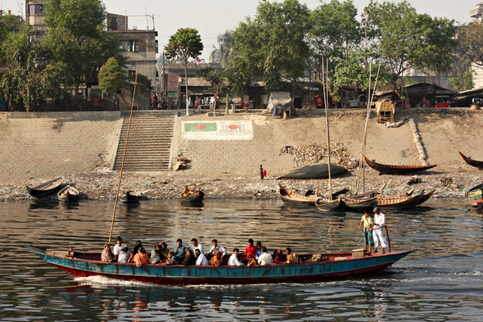 Bangladesh.  Boat on a river with some buildings on the bank