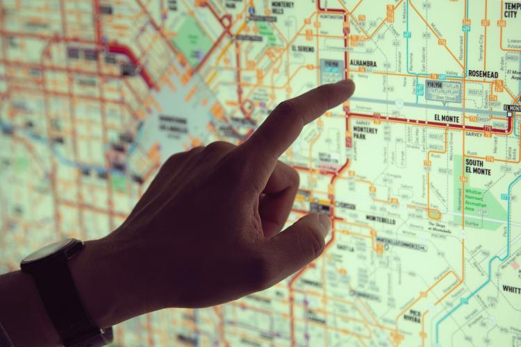 finger pointing to a location on a lit map of Los Angeles