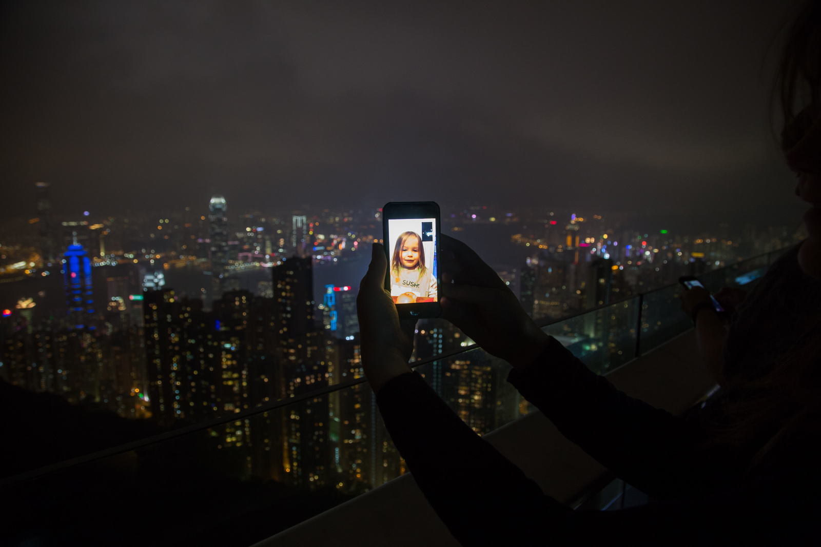 A child shown on facetime in front of the hong kong skyline at night