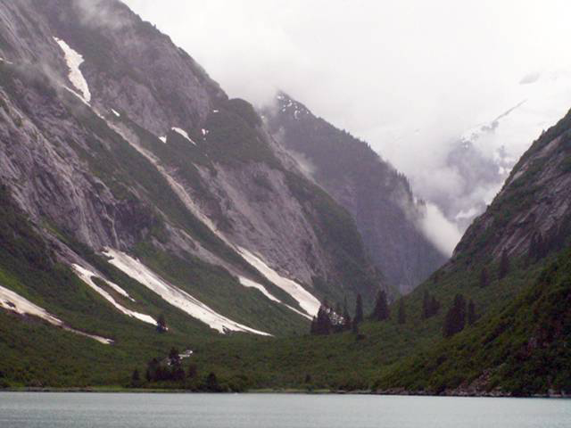 U-shaped valley in Tracy Arm Wilderness Area, Alaska. Thick cloud cover, highway in foreground.