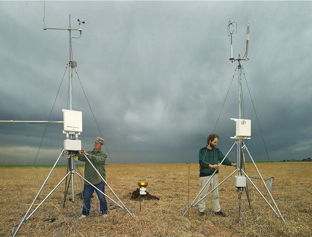 two men setting up anemometers in the field