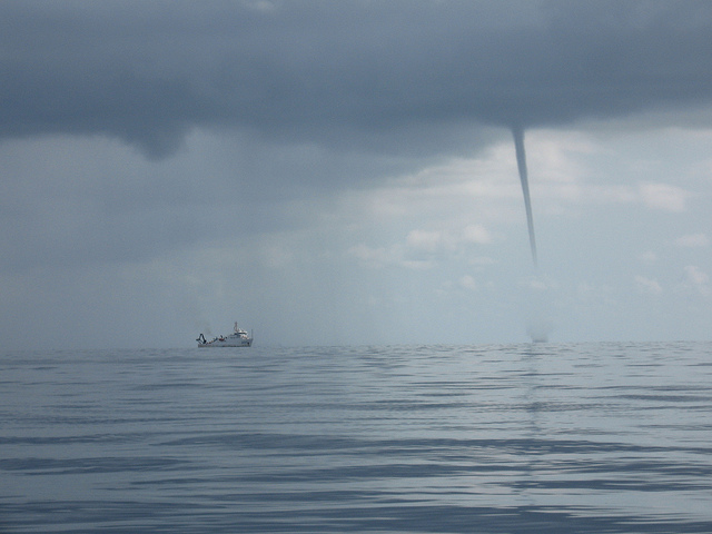 water spout over water next to boat