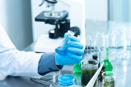 Scientific figure holding flask with blue liquid