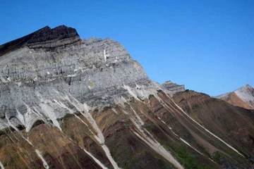 rock formation where top half is grey and bottom half is maroon. The entire formation has horizontal striations