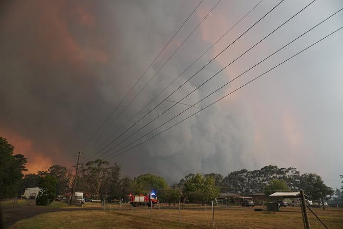 Huge smoke cloud and light from the fires. Fire engine in the foreground