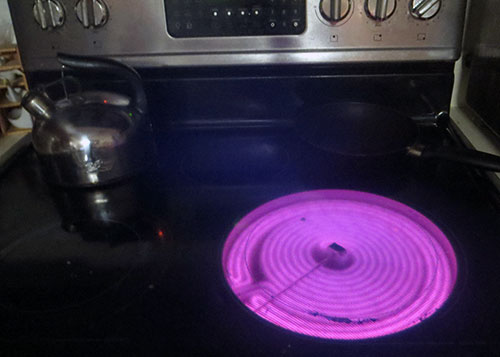 Electric stove burner glowing pink.