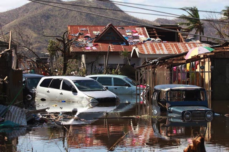 Four cars sitting in deep water outside of storm damaged homes.