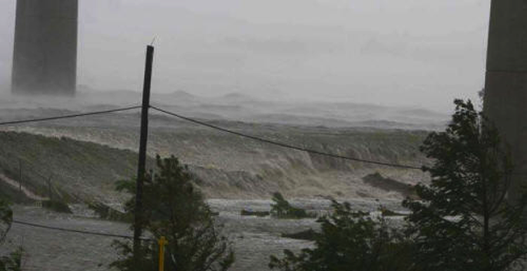 Storm surge waves striking the top of protective levee.