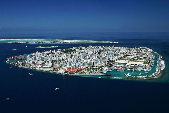 Low-lying island in the Maldives with high-rises and other buildings occupying all available land space.