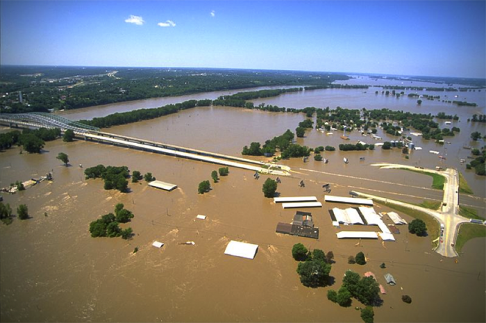 photograph showing multiple homes under water and a highway interchange that is partially under flood waters.