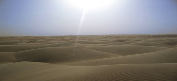photograph showing the sky above barren sand dunes that fill the rest of the picture.