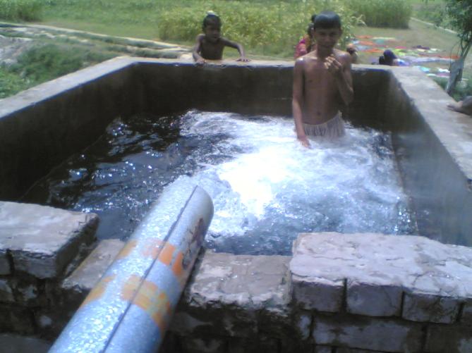 Pipe spewing water into a stone basin with a child standing in it
