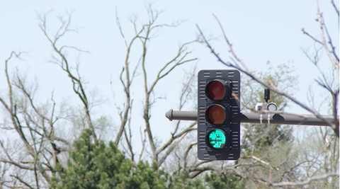Stoplight signaling green. Being held up higher in the air.