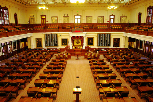 Minnesota legislative chambers. Many chairs and desks with a raised head seating area and a podium in the center of the room.