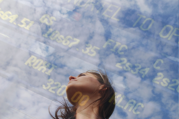 Daydreamer looking at the sky, superimposed with an image of the stock exchange