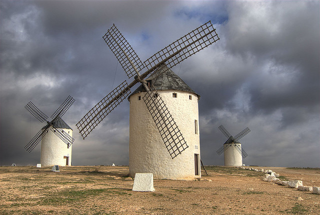 3 windmills in a field backed by a stormy sky