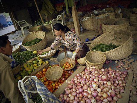 A woman selling fruits and vegetables at a market.