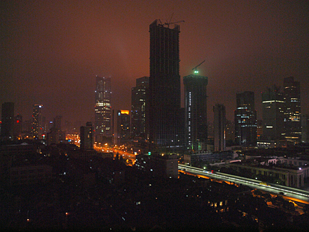  city skyline with buildings lit up and the sky is dark, smoggy and slightly orange from all the lights
