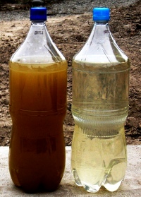 bottles containing wastewater before (dark brown) and after treatment(clearish yelow)