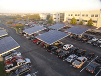 Large parking lot. Some of the cars are shaded with PV covers.