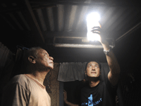 A man inspects a solar light bulb made from a discarded plastic soda bottle.