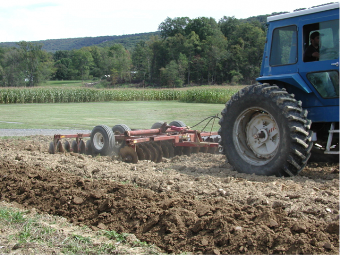 Disk plow breaking up soil clods in a secondary tillage operation