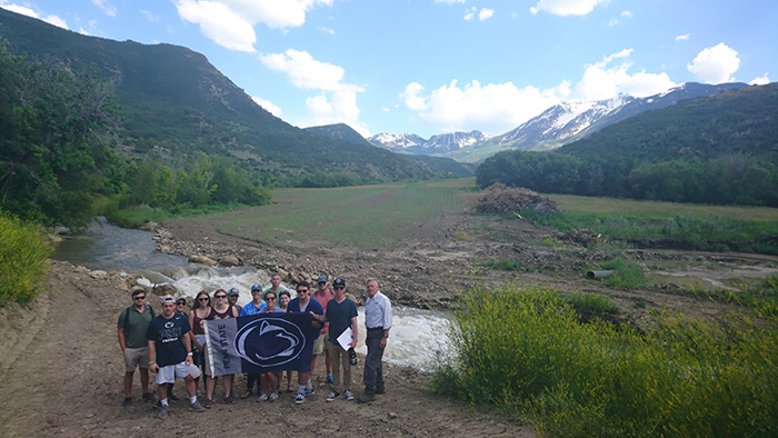  A group of Penn State students standing in front of mountain scenery with a Penn State flag