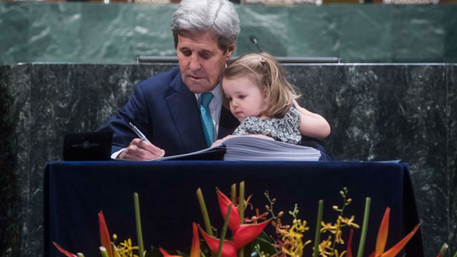 Secretary of State, John Kerry signs the Paris Agreement with his granddaughter on his lap