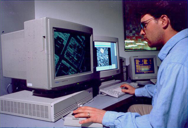 Man sitting at a computer with a map on it. Digital photogrammetric workstation.