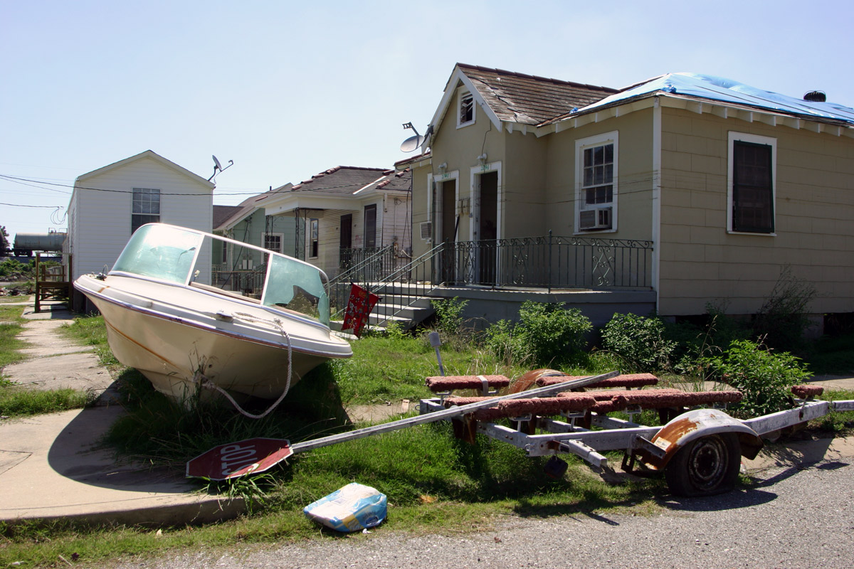 Scene of Hurricane Katrina damage, wreckage and a boat sideways in front of a house