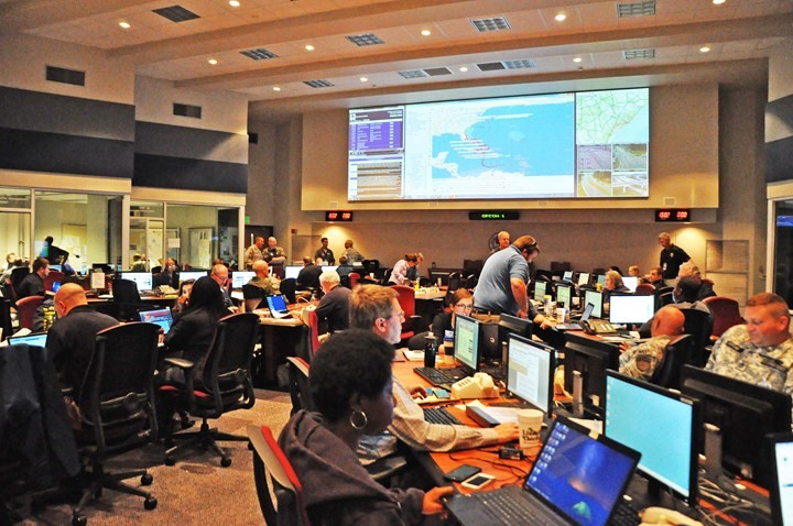 Conference room. Maps on screen in front and about 50 people working on computers