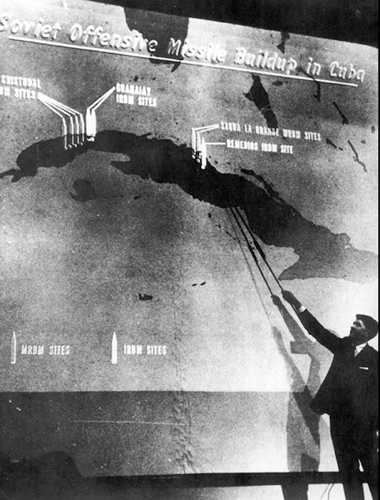 government offical points to chart depicting soviet missile sight locations on Cuba