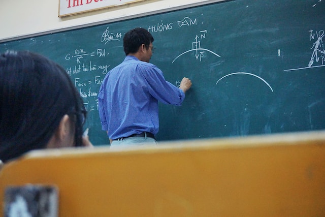 person applying knowledge by writing diagrams on chalkboard