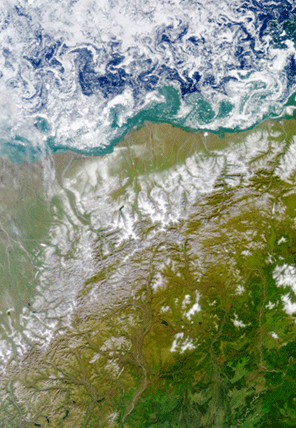 Satellite image of ANWR.  To the north (top) sea ice floats in the Beaufort Sea.  Below, rivers drain from snow covered mountains.