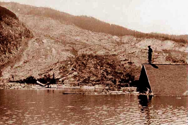 Historical photo of lower slide lake shows a person standing on the roof of a submerged building
