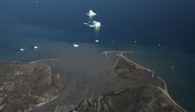Arial view of delta near Muddy Bay, Greenland. Stream flows in braided pattern and there are icebergs offshore