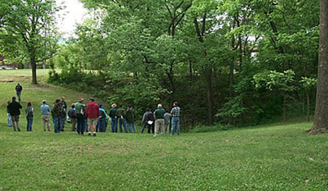 Group of about 20 people standing by sinkhole, near Shenandoah National Park