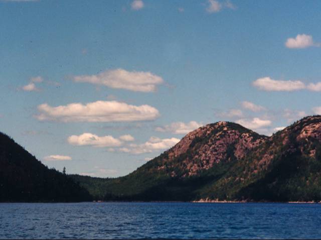 Blue waters of Jordon Pond with Bubble Mountains in background, under pale blue cloudy sky