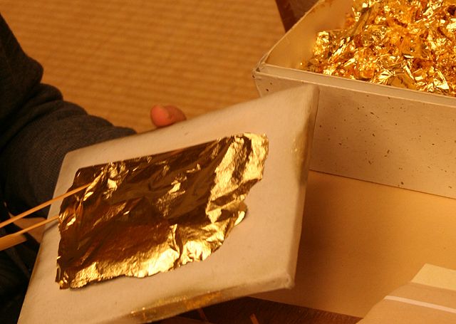 Man holding a tile with a piece of gold layed on top