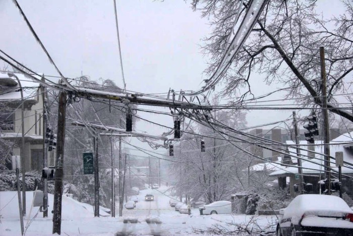 Photograph of a city neighborhood where power lines and trees are encased in ice. 