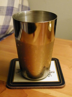 A photograph of a cup with liquid water drops covering part of the outside.