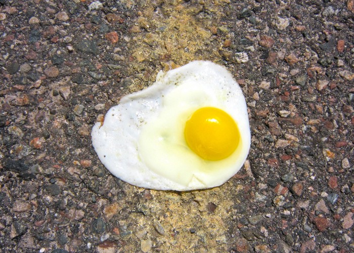 Fried egg on an asphalt surface.