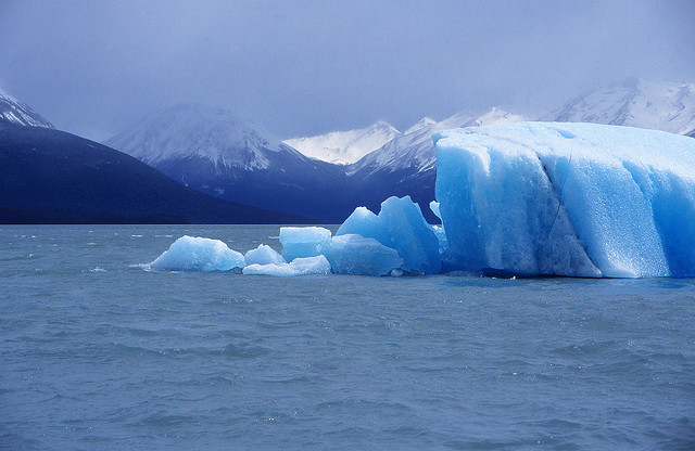 Ghiacciaio in una baia circondata da montagne. Il ghiacciaio ha un colore blu.