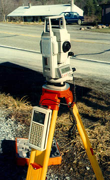Photo of a Total station next to a road (device mounted on an orange tripod)