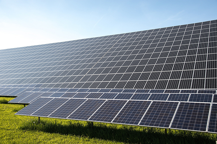 Close up of solar panels sitting in a field with sun shining